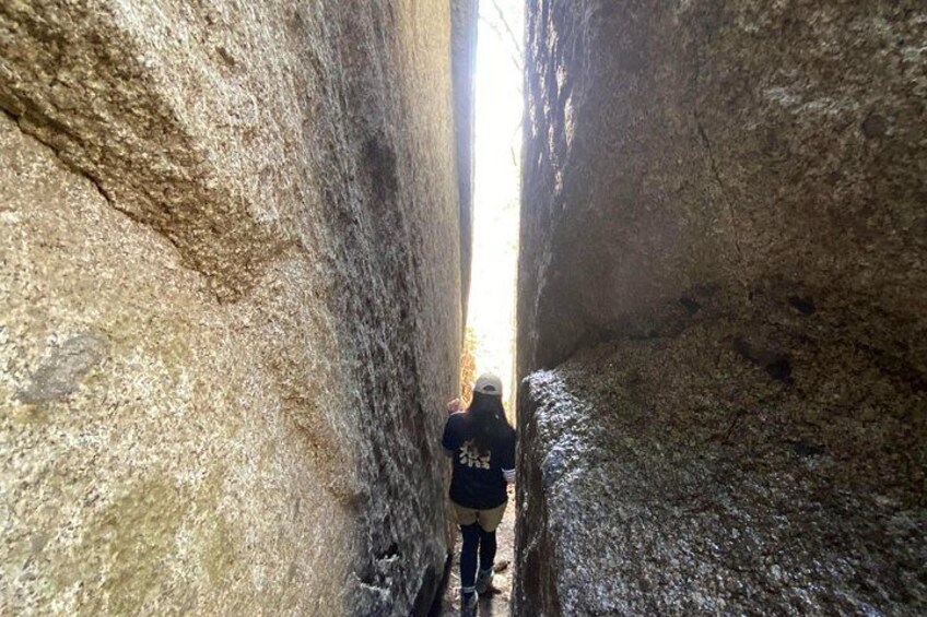 A person standing in a narrow passageway between large rock walls. 5