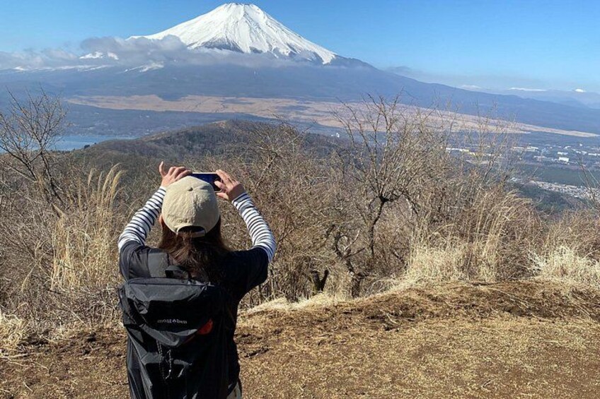 A person taking a photograph of a snow-capped mountain with a clear sky. 2