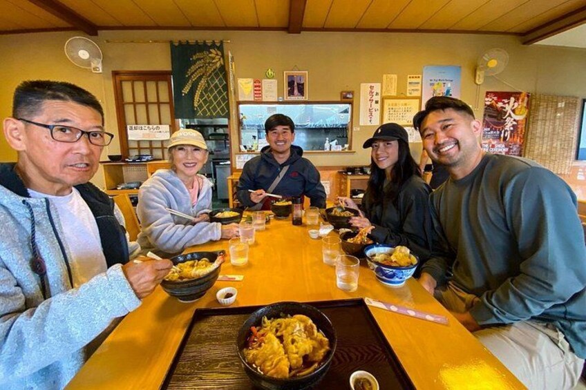 A group of people dining at a restaurant with a wooden table and various dishes. 3