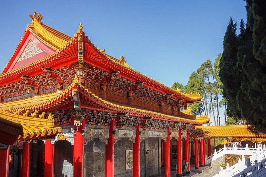 A traditional Chinese temple with red and yellow roofs, ornate decorations, and a white fence. 2