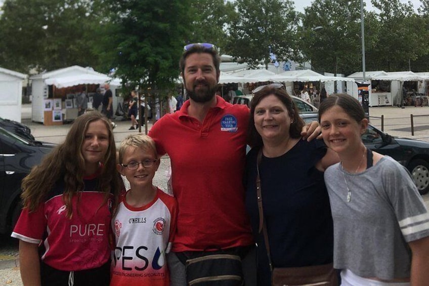 Eine Gruppe von Menschen posiert für ein Foto bei einer Veranstaltung im Freien, im Hintergrund sind Zelte und Essensstände zu sehen. 3