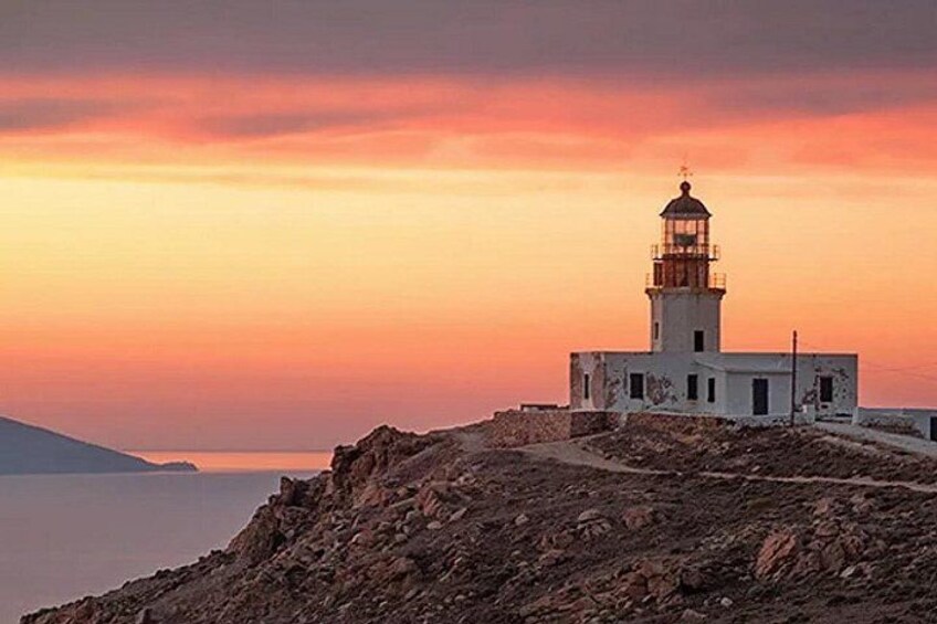 A lighthouse on a rocky cliff with a sunset in the background. 1