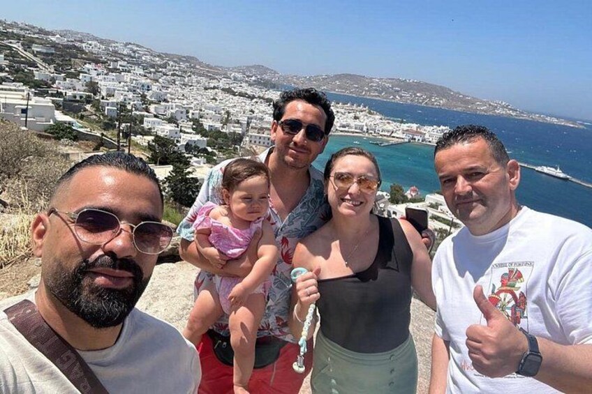 A group of people on a hill overlooking a coastal town with white buildings and a clear view of the sea. 3