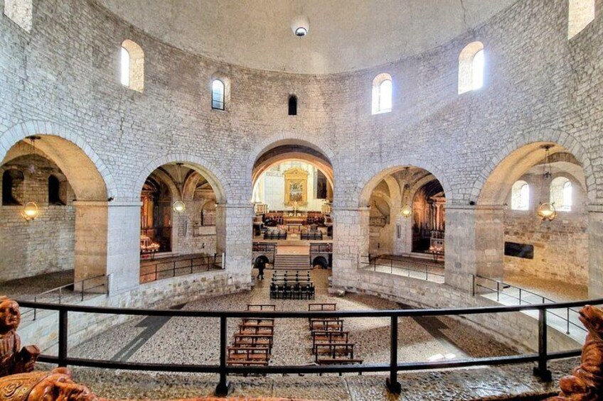 An interior with stone arches, a central aisle, and a view of a church altar. 2