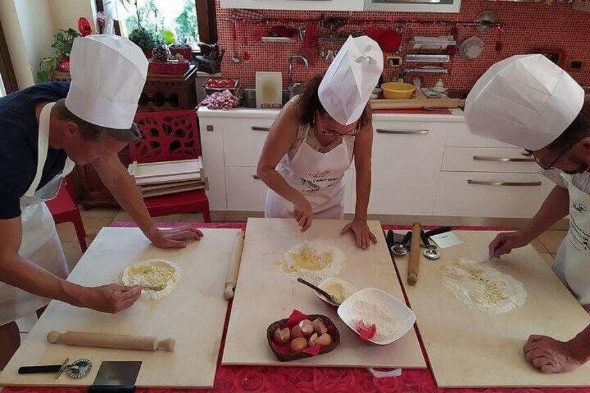 Tres personas en una cocina preparando comida, con ingredientes y utensilios sobre la encimera. 2