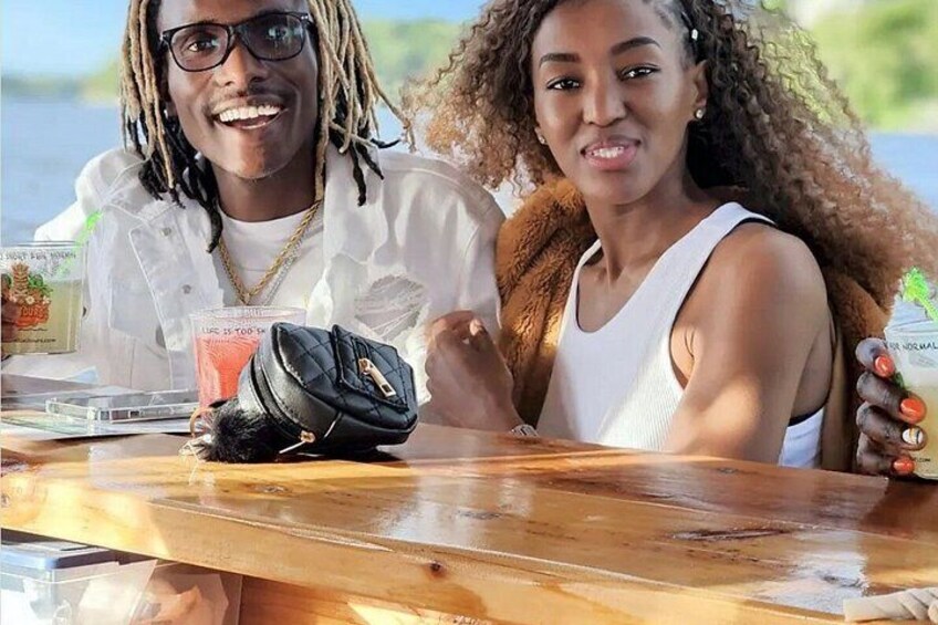 Two people sitting at a wooden table with drinks and a book. 2