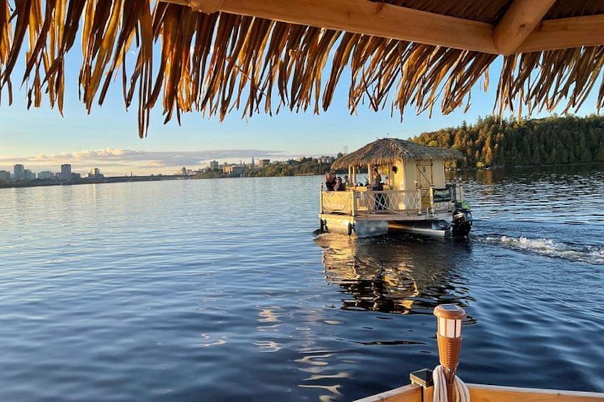 A boat with a thatched roof moving on a calm body of water, with a city skyline in the background. 2