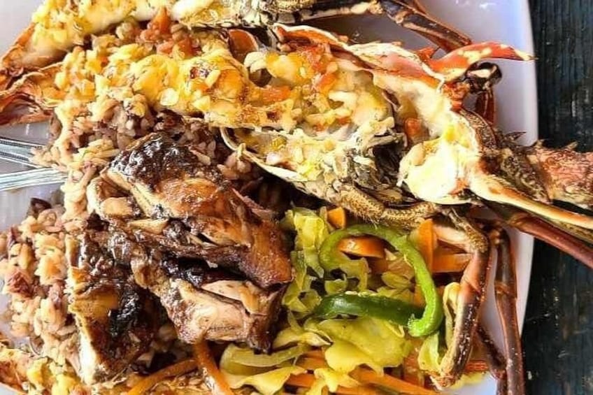 A plate of food with crab legs, chicken, and vegetables. 3