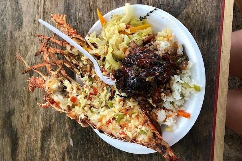 A plate of food with a lobster, rice, and vegetables. 2