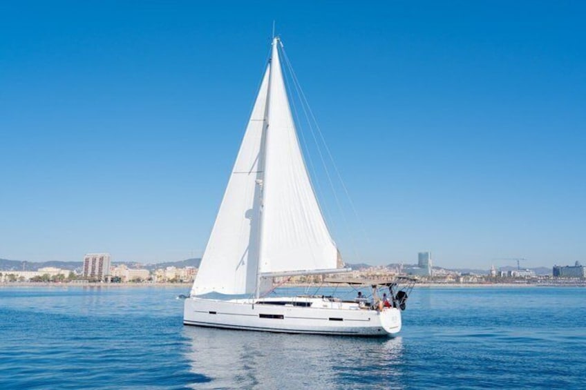 A white sailboat on calm blue water with a city skyline in the background. 2