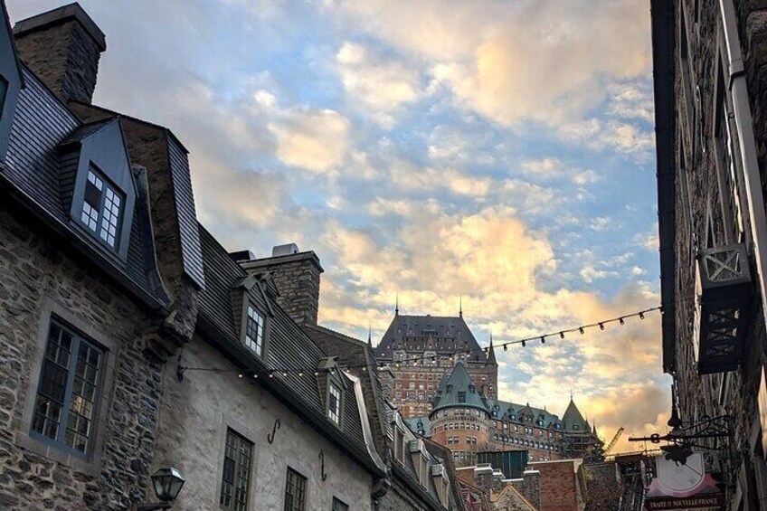 A historic town with stone buildings and a prominent castle in the background. 1