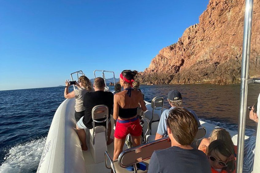 A boat with people on board, rocky cliffs in the background, and calm water. 5