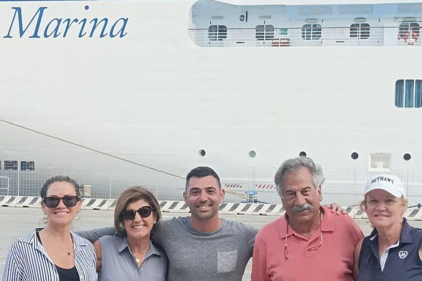 Un grupo de personas de pie frente a un barco grande con la palabra 'Marina' a la vista. 5