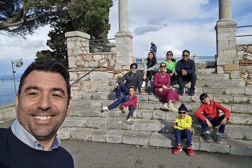 Un grupo de personas sentadas en escalones de piedra, con una masa de agua al fondo. 2