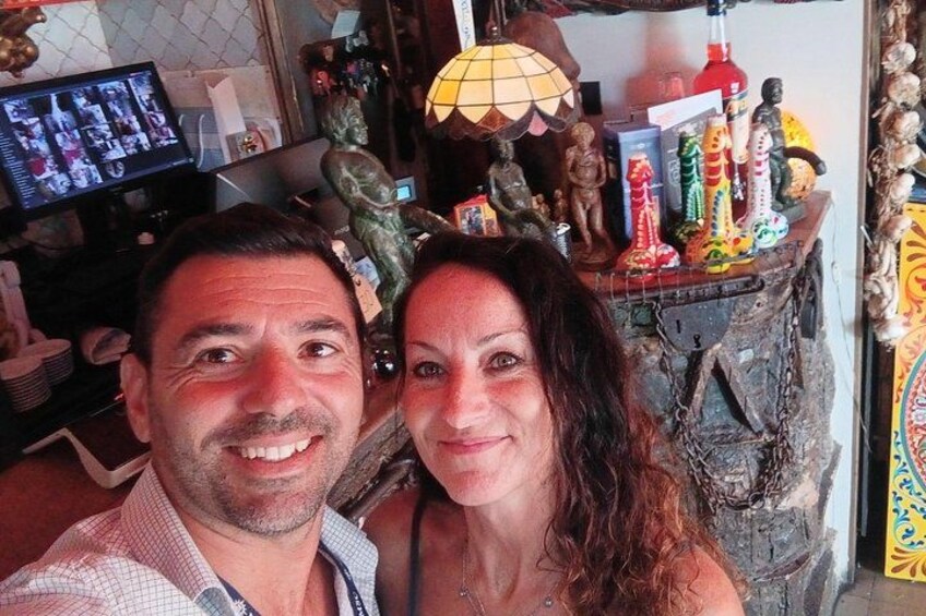 Un hombre y una mujer en una habitación con un estante desordenado que contiene varias figuritas y una lámpara. 3