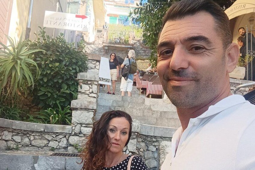 Un hombre y una mujer frente a una escalera de piedra, con un restaurante al fondo. 4
