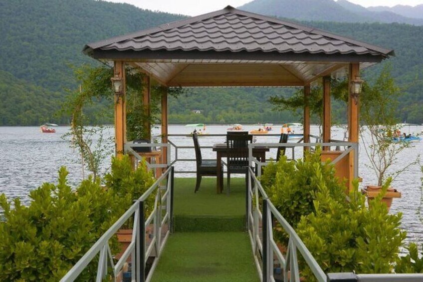 A gazebo with a tiled roof overlooking a lake with boats. 5