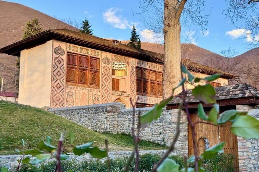 A traditional building with intricate patterns and wooden doors, set against a mountainous backdrop. 4