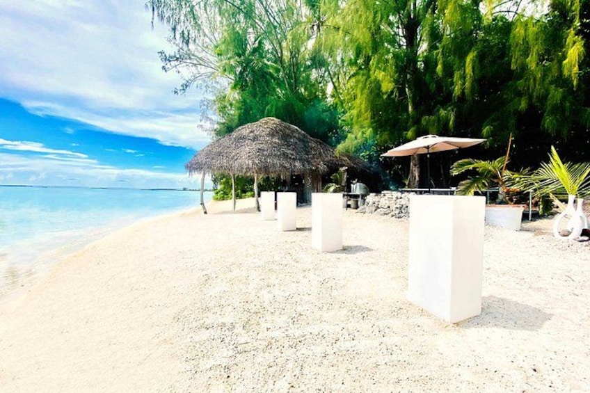 A beach with thatched huts, palm trees, and a clear sky. 2