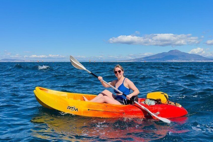 A person kayaking on a body of water with a mountain in the background. 4