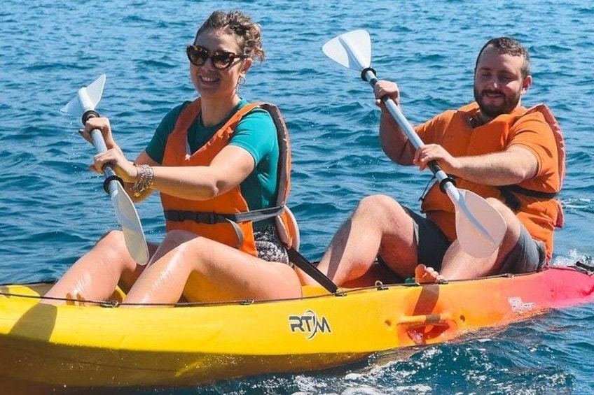 Two people kayaking on a yellow raft with a blue ocean in the background. 2