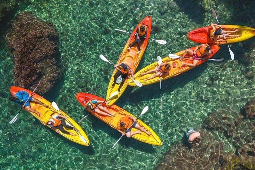 Kayakers in yellow and red kayaks on clear water. 2