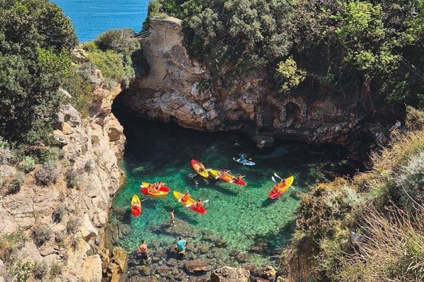 A coastal cove with kayaks, rocky cliffs, and clear water. 3