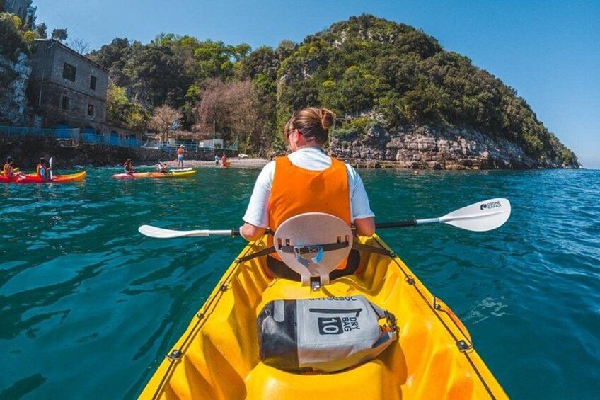 A person kayaking on clear water with a rocky island in the background. 4