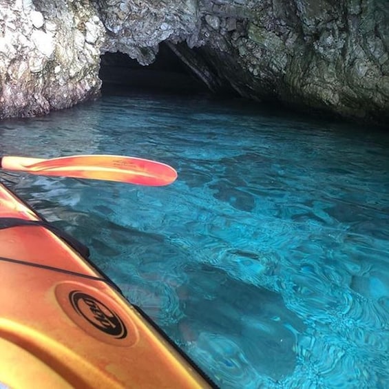 A kayak in clear water with a rocky cave entrance. 2