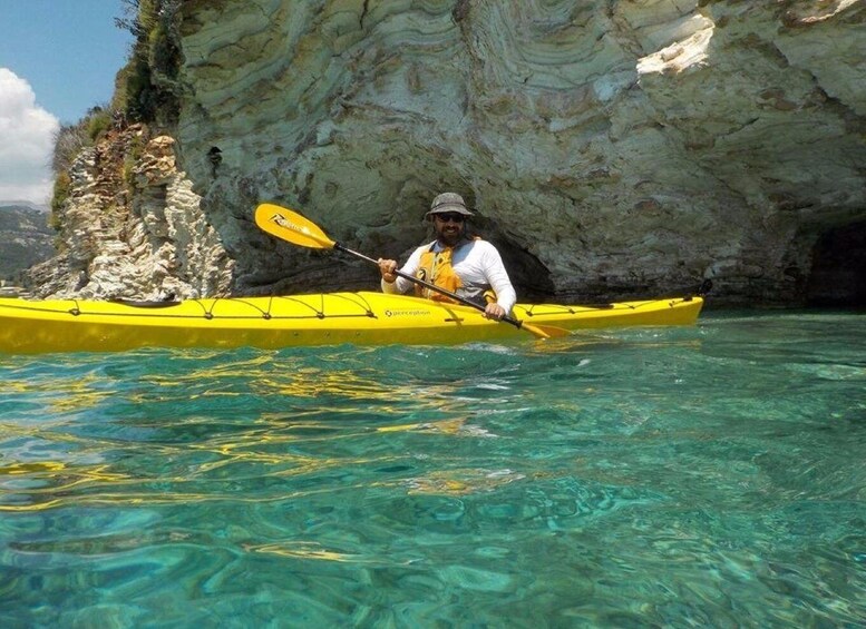 A person kayaking in clear water with a rocky cliff in the background. 4