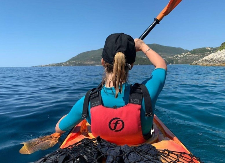 A person kayaking on a calm sea with a mountainous landscape in the background. 5