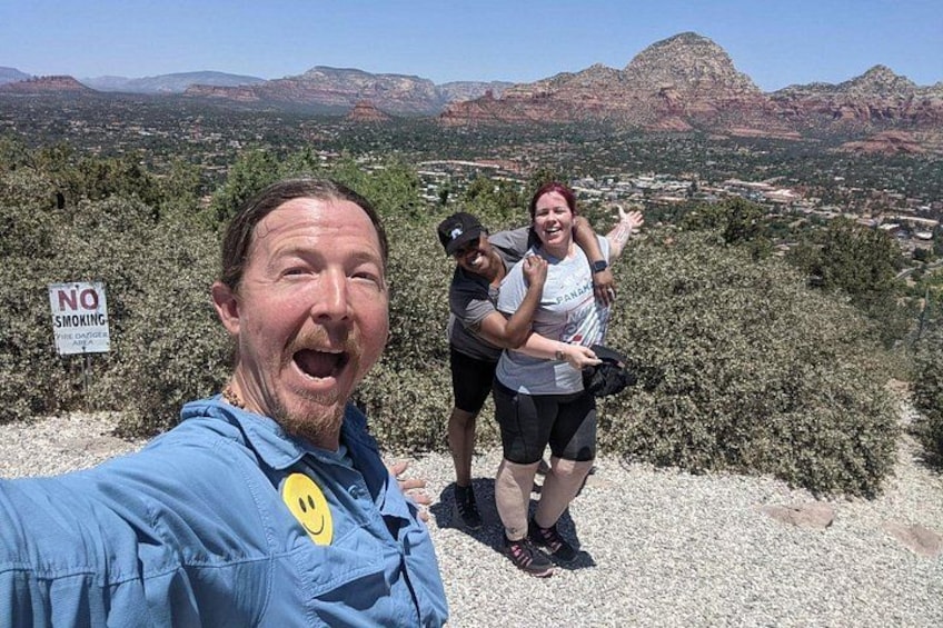 A person taking a selfie with a scenic view of mountains and a 'NO SMOKING' sign in the background. 4