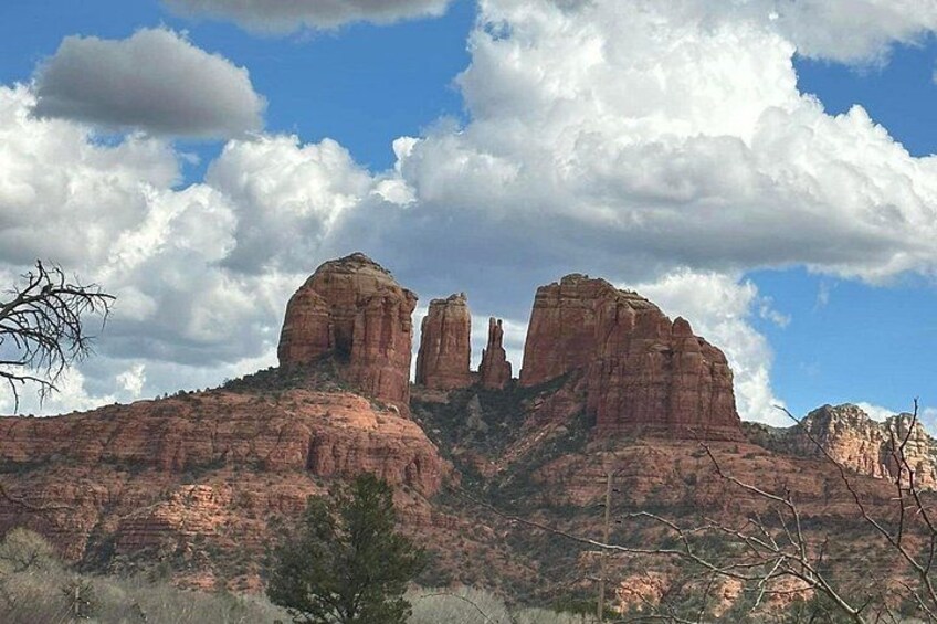A mountain range with prominent red rock formations and a clear blue sky with clouds. 2