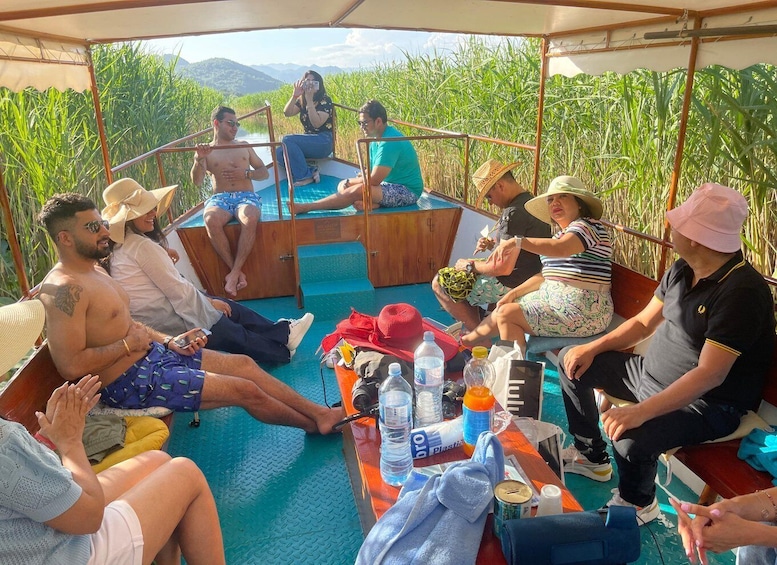 A group of people sitting on a boat with a view of tall grass and mountains in the background. 4