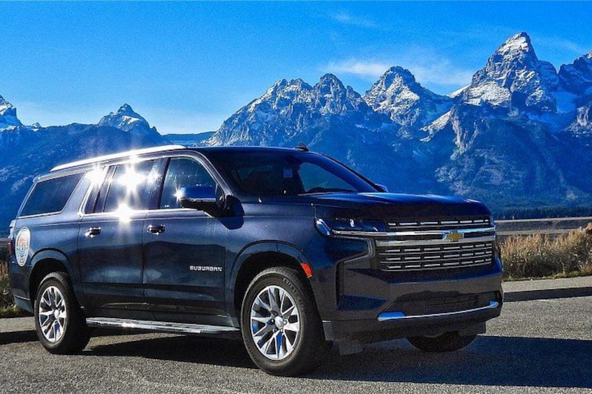 A dark-colored SUV parked on a road with a mountainous landscape in the background. 2