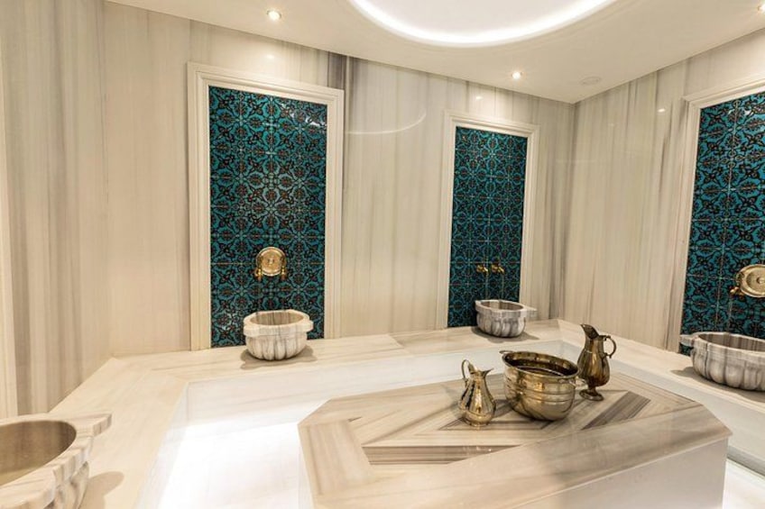 Une salle de bain luxueuse avec un meuble-lavabo en marbre, un grand miroir et des carreaux décoratifs. 1