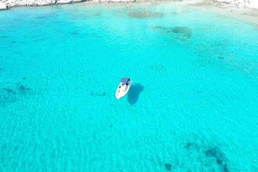 Un mar turquesa transparente con una embarcación flotando en la superficie. 2