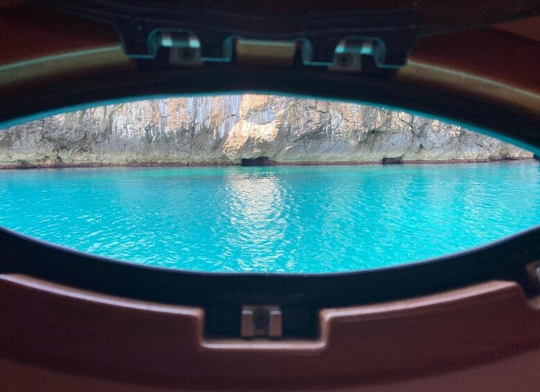 A circular window with a turquoise pool and a rocky wall in the background. 4