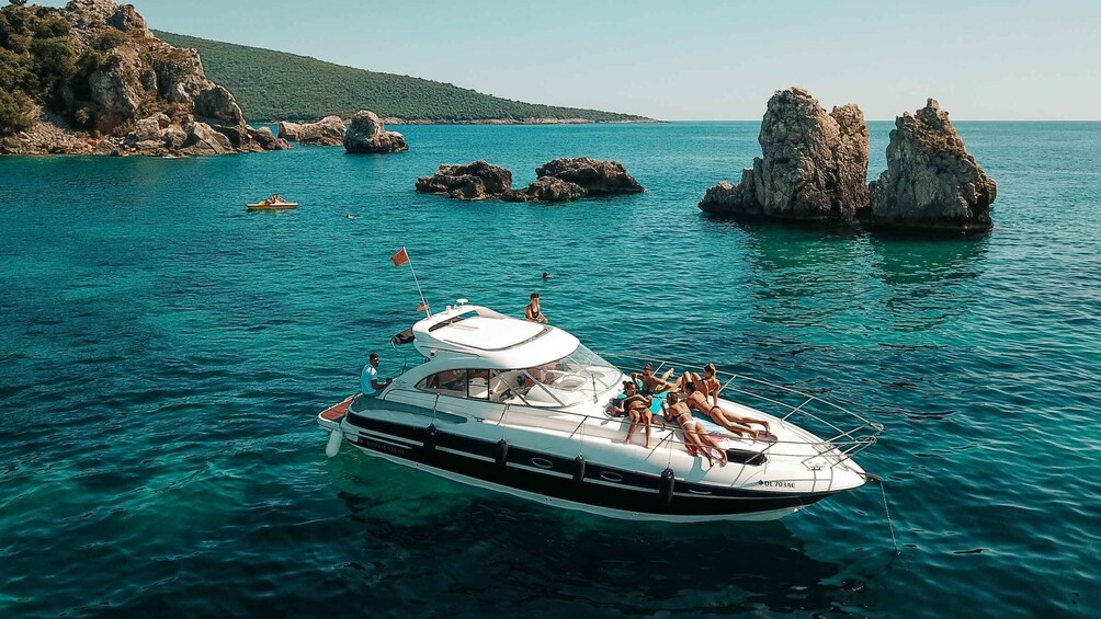A boat with people on it in clear blue water near rocky outcrops. 1