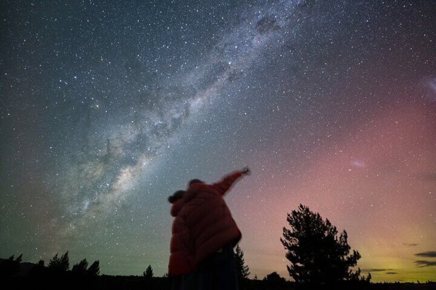 A person pointing at the night sky with stars and the Milky Way visible. 1