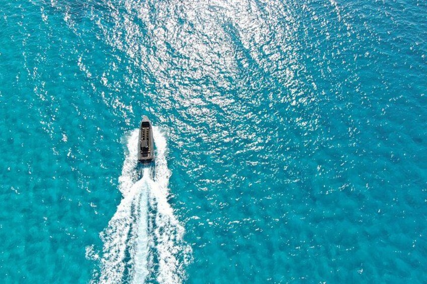 A boat creating a wake in turquoise water. 2