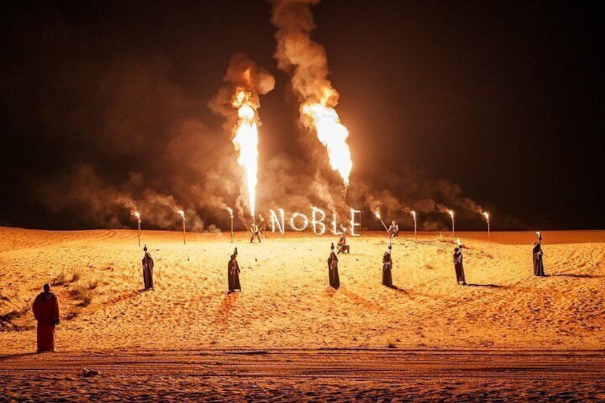 A desert scene with multiple fires and people in traditional attire. 1