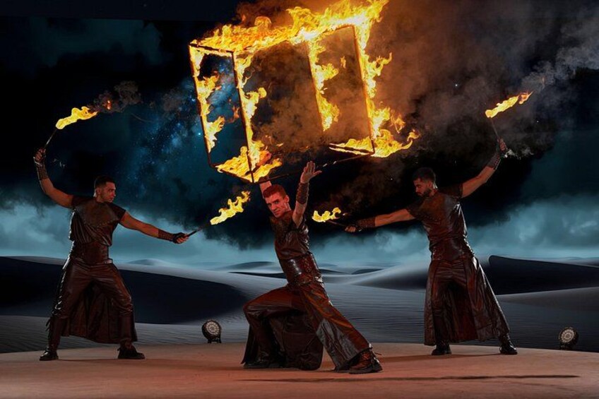 Three individuals performing with fire props in a desert setting. 3