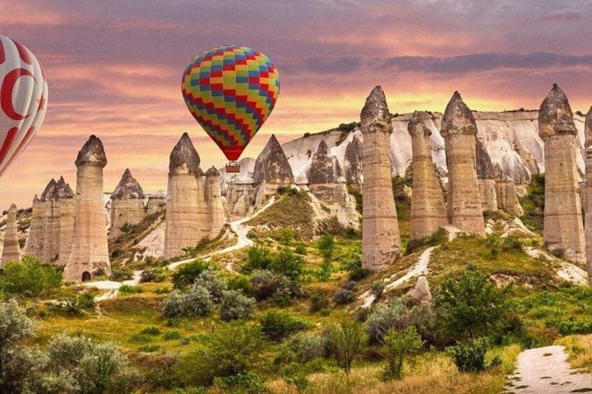 Paesaggio con alte formazioni rocciose appuntite e una colorata mongolfiera nel cielo. 4