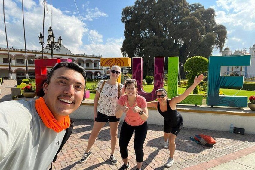 Un grupo de personas posando frente a un letrero colorido con la palabra 'LOVE' en letras grandes. 3