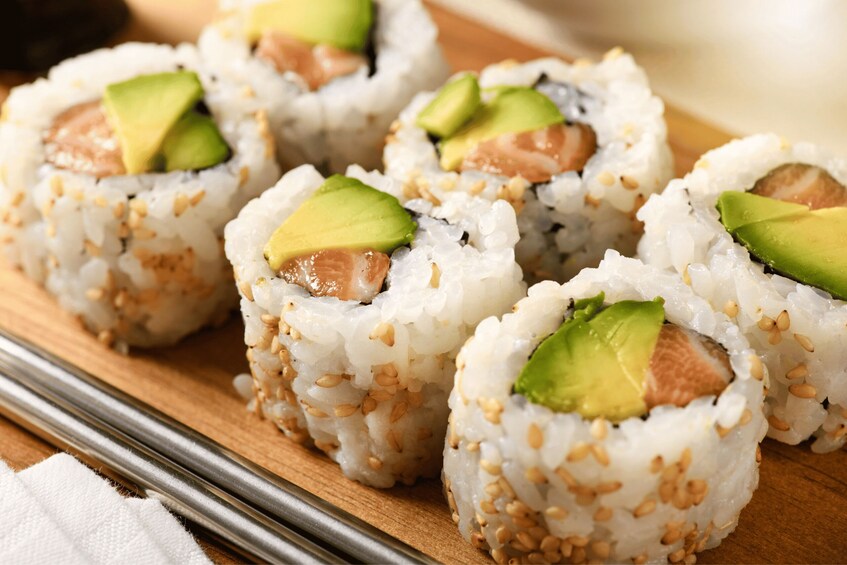 Sushi rolls with avocado and sesame seeds on a wooden board. 5