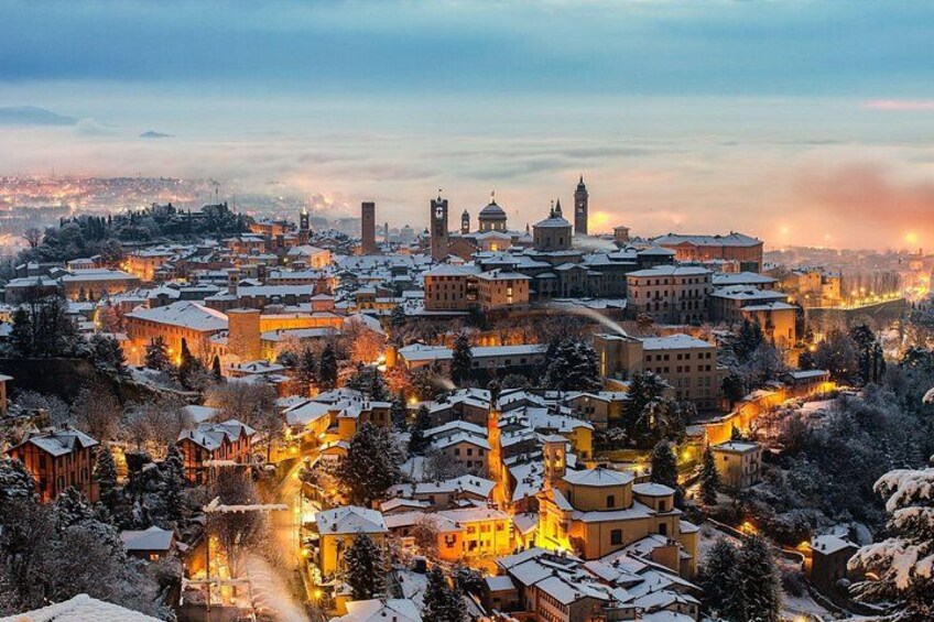 A snow-covered town with illuminated buildings and a prominent tower. 2