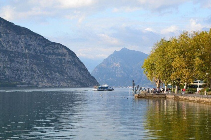 A calm lake with a boat, mountains in the background, and a tree-lined shore. 5