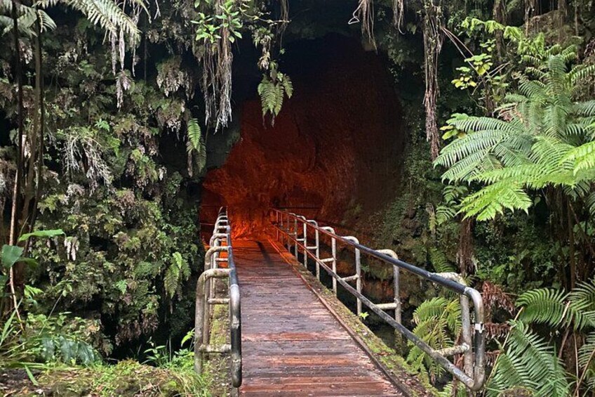Un puente de madera con barandillas metálicas que conduce a una cueva. 1