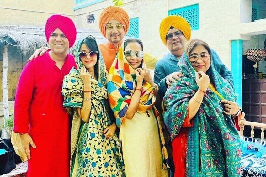 A group of people in traditional attire standing in front of a building with blue and white walls. 1